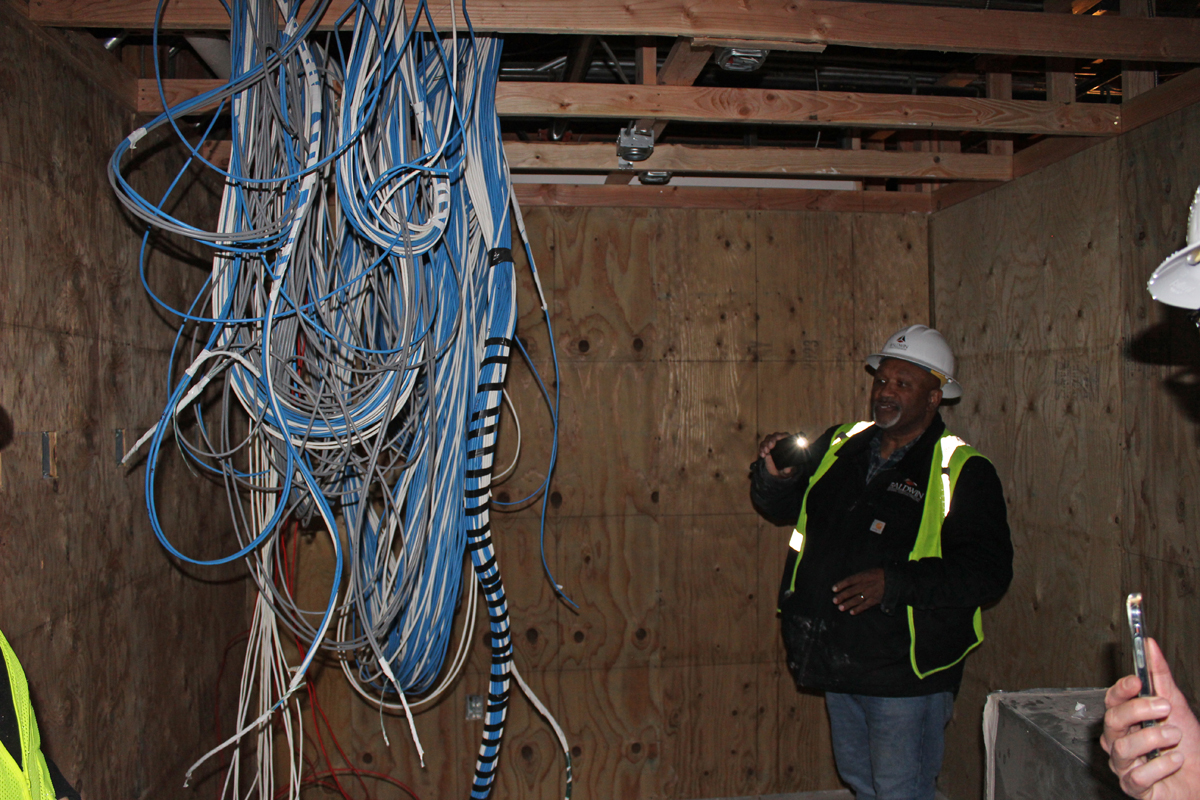 Construction manager shines flashlight on wires that will soon become the heart of the new early learning center's technology infrastructure