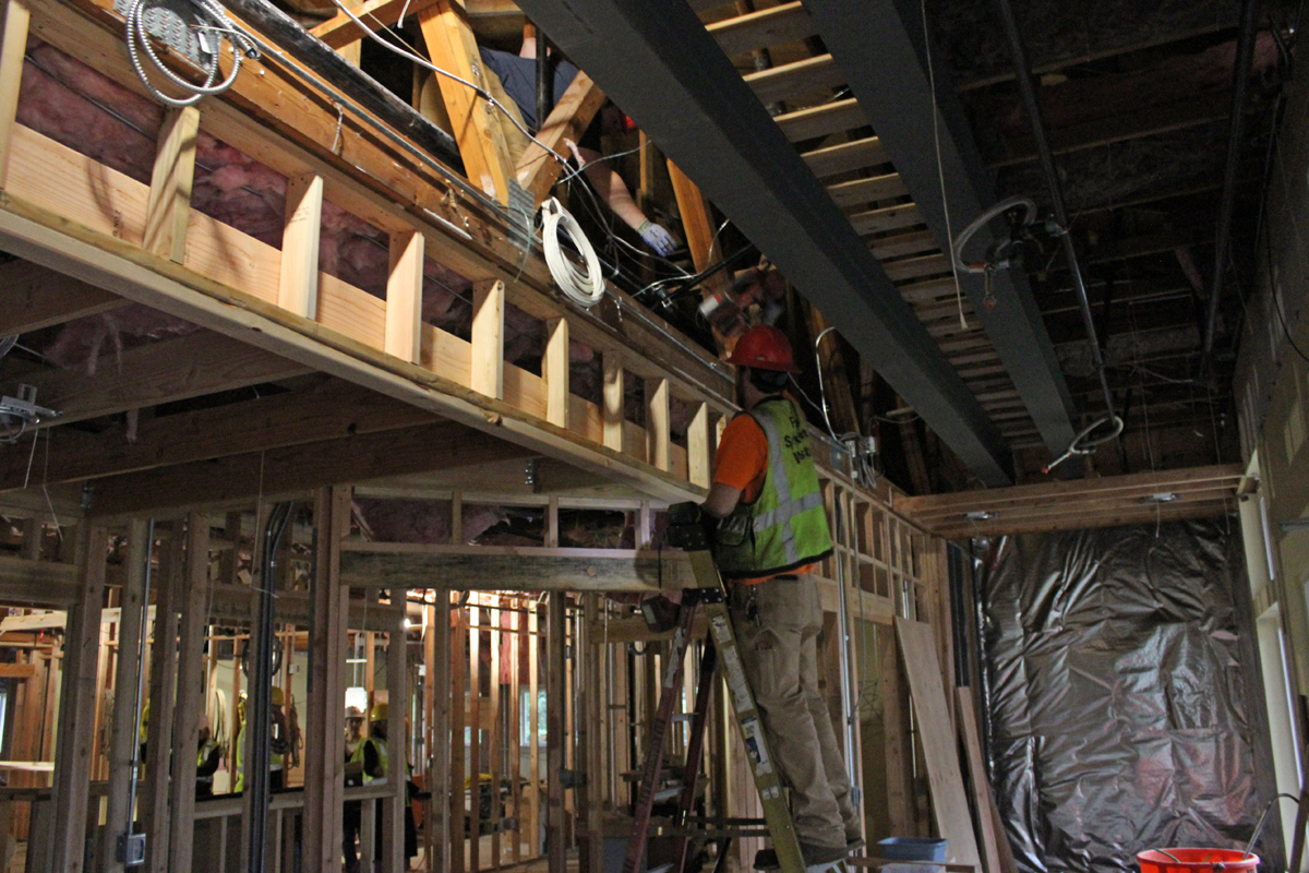 Construction worker working on a ladder in what will become the main floor reception and waiting area of the new early learning center