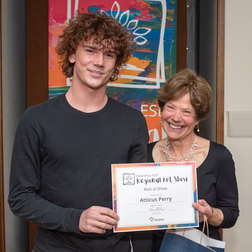 Best of Show winner Atticus Perry holds his award certificate and poses with Clackamas ESD Board Vice Chair Linda Brown