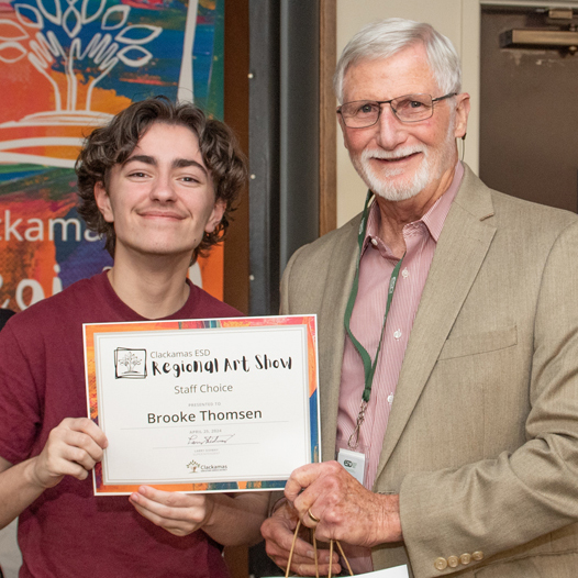 Staff Choice winner Brooke Thomsen holds his award certificate and poses with Clackamas ESD Board Chair Greg MacKenzie