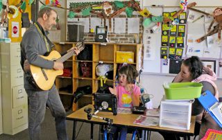 Steve Schroeder, LEEP teacher, playing guitar during a class lesson to the delight of a clapping student